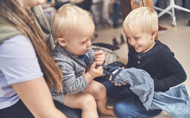 To børn og en voksen sidder på gulvet