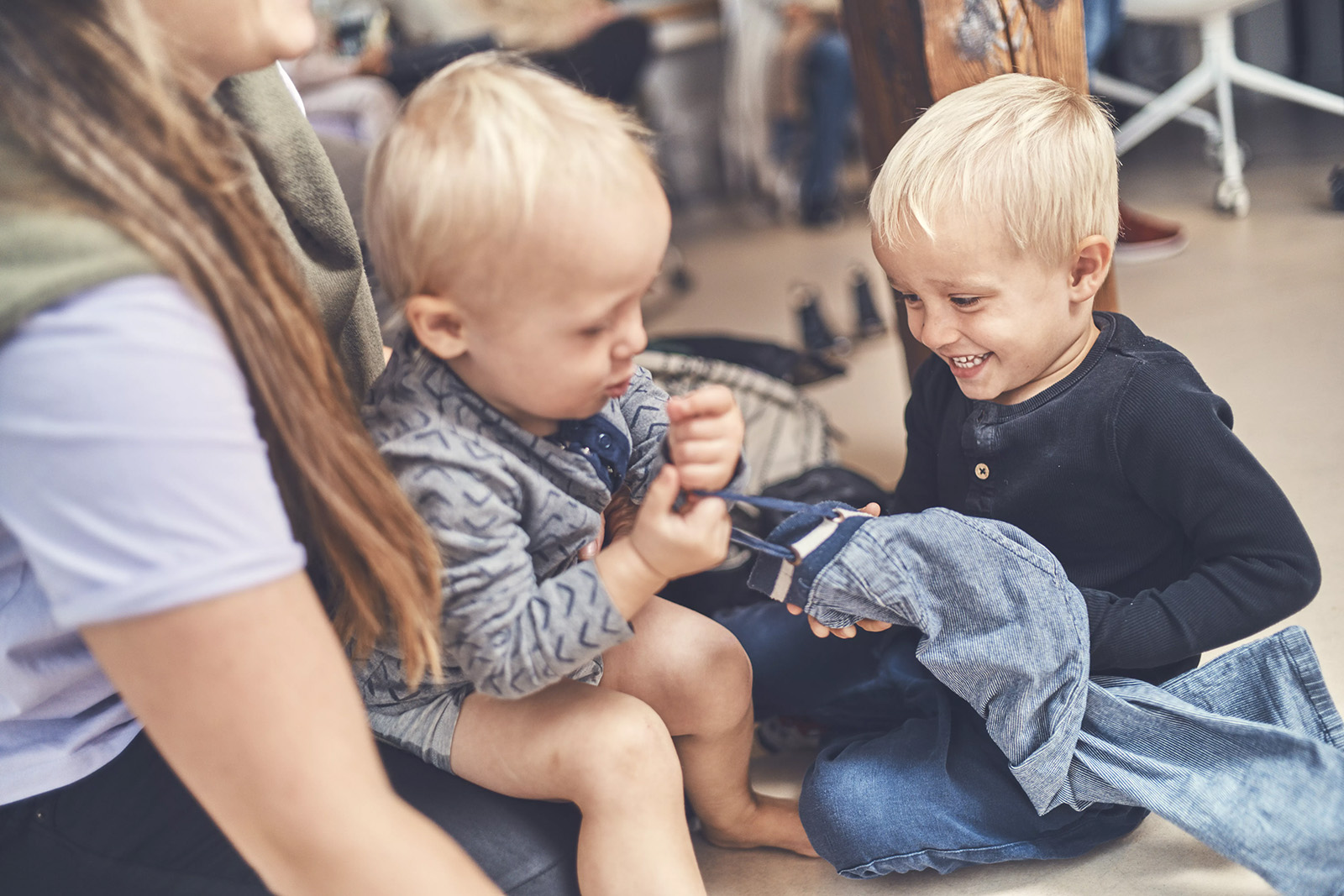 To børn og en voksen sidder på gulvet