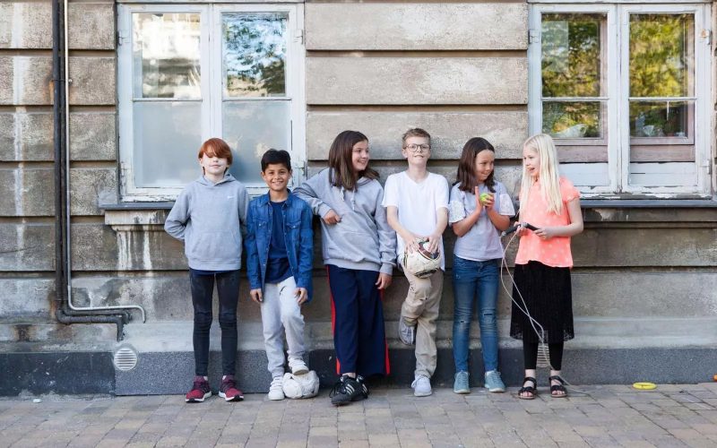 Fire børn står op ad en mur