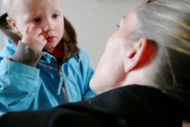 Dame kigger på barn i blå jakke