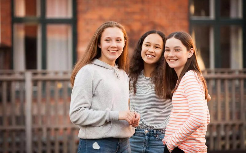 Tre piger står foran et hegn