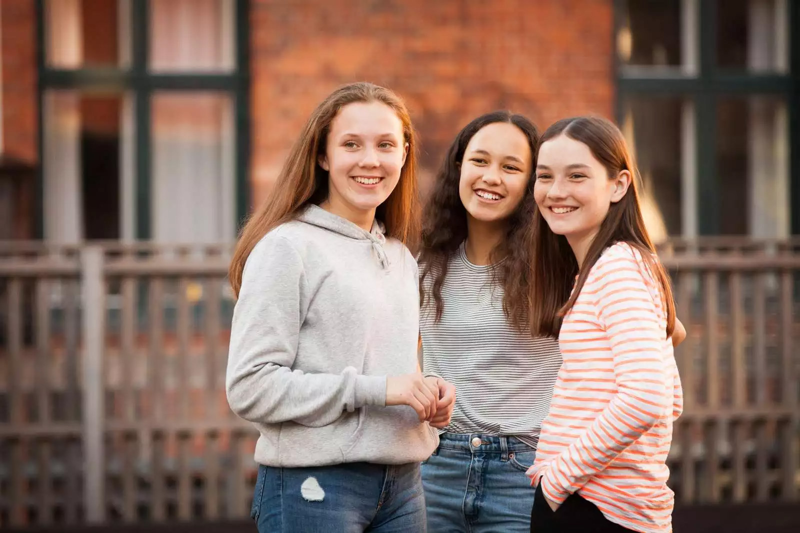 Tre piger står foran et hegn