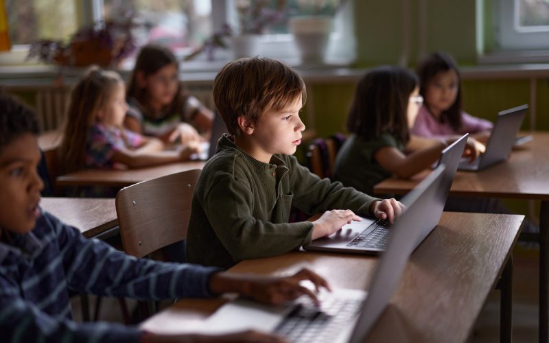 Dreng sidder på laptop i et klasselokale