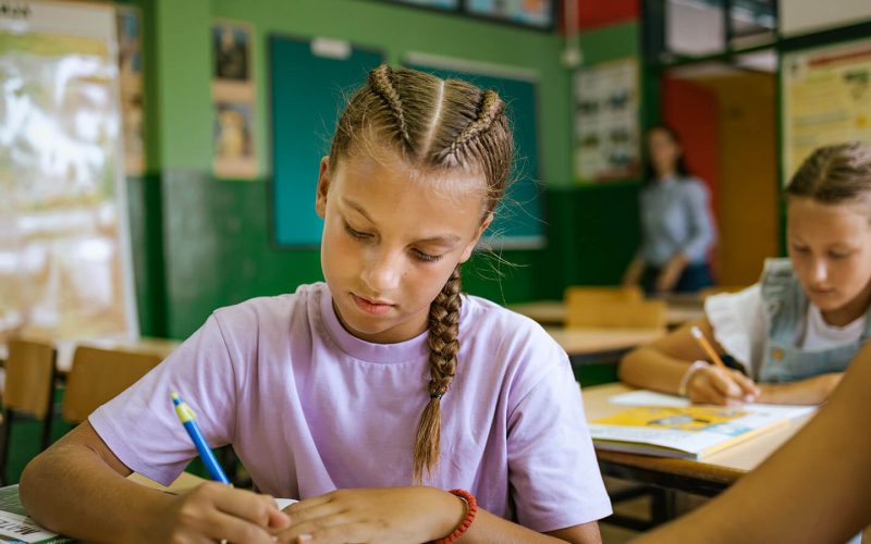 Pige sidder i klasselokale og skriver