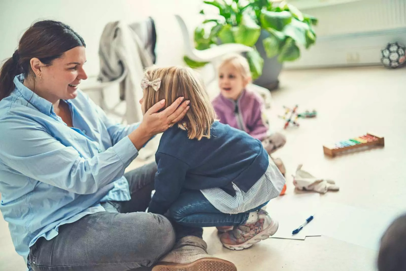 Kvinder sidder på gulvet med et barns hoved i hænderne